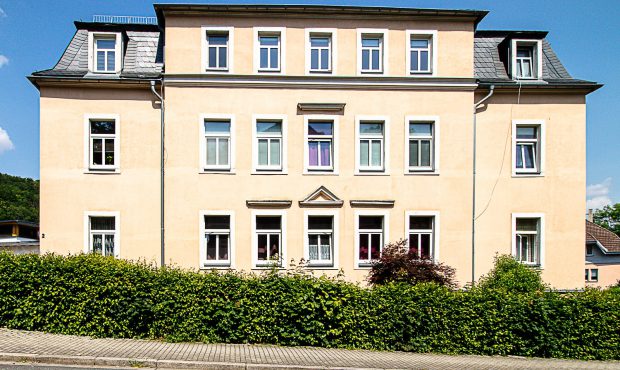 Bestandsimmobilie Freital, Außenansicht des Mehrfamilienhauses mit Hecke