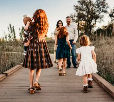 Eltern mit vier Kindern laufen auf einem Steg in der Natur