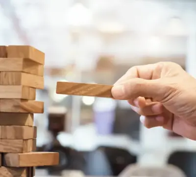 Mann entnimmt Stück aus einem Jengaturm