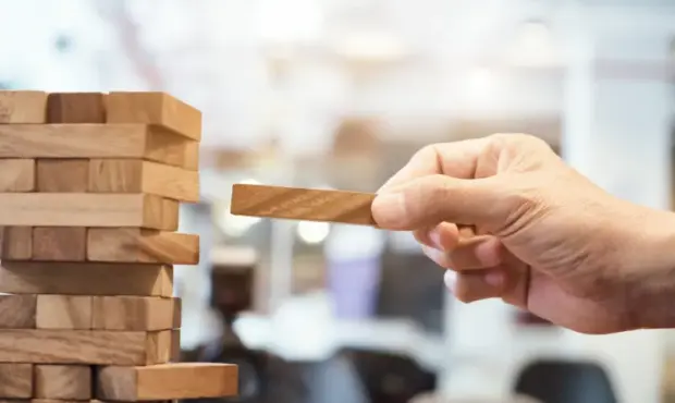 Mann entnimmt Stück aus einem Jengaturm