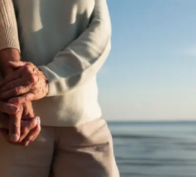 Älteres Paar steht am Strand und hält Hände