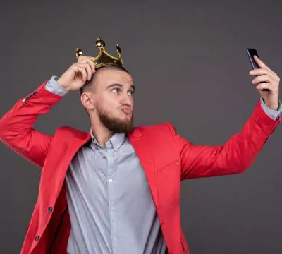Mann in rotem Sakko und Krone schießt ein Selfie