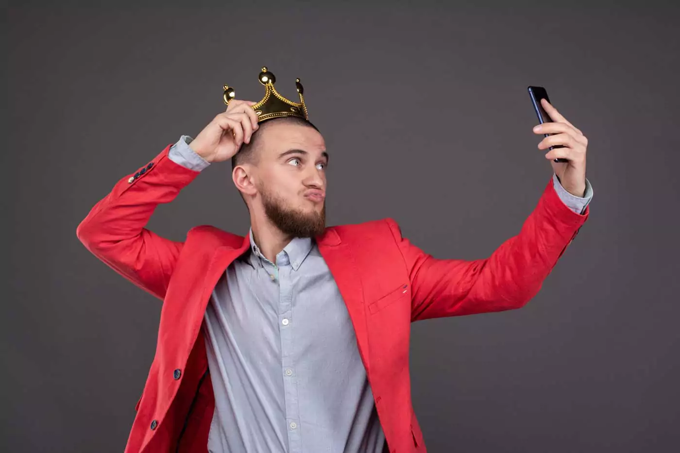 Mann in rotem Sakko und Krone schießt ein Selfie