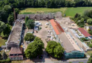 Von grünen Wäldern umgebene Baustelle des Klosters Zinna aus der Vogelperspektive