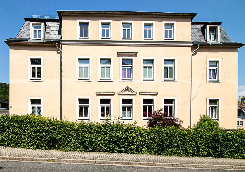 Bestandsimmobilie Freital, Außenansicht des Mehrfamilienhauses mit Hecke