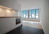 Bestandsimmobilie Dresden-Neustadt, Innenansicht Einbauküche mit Blick auf den Wohnbereich und die Fensterfront mit Außenjalousie