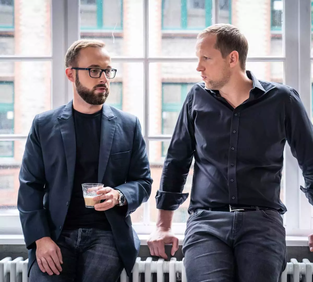 Fabian Schuster (links) mit Kaffeglas, Marc, beide an einem Fensterbrett lehnend s Jurowski (rechts)
