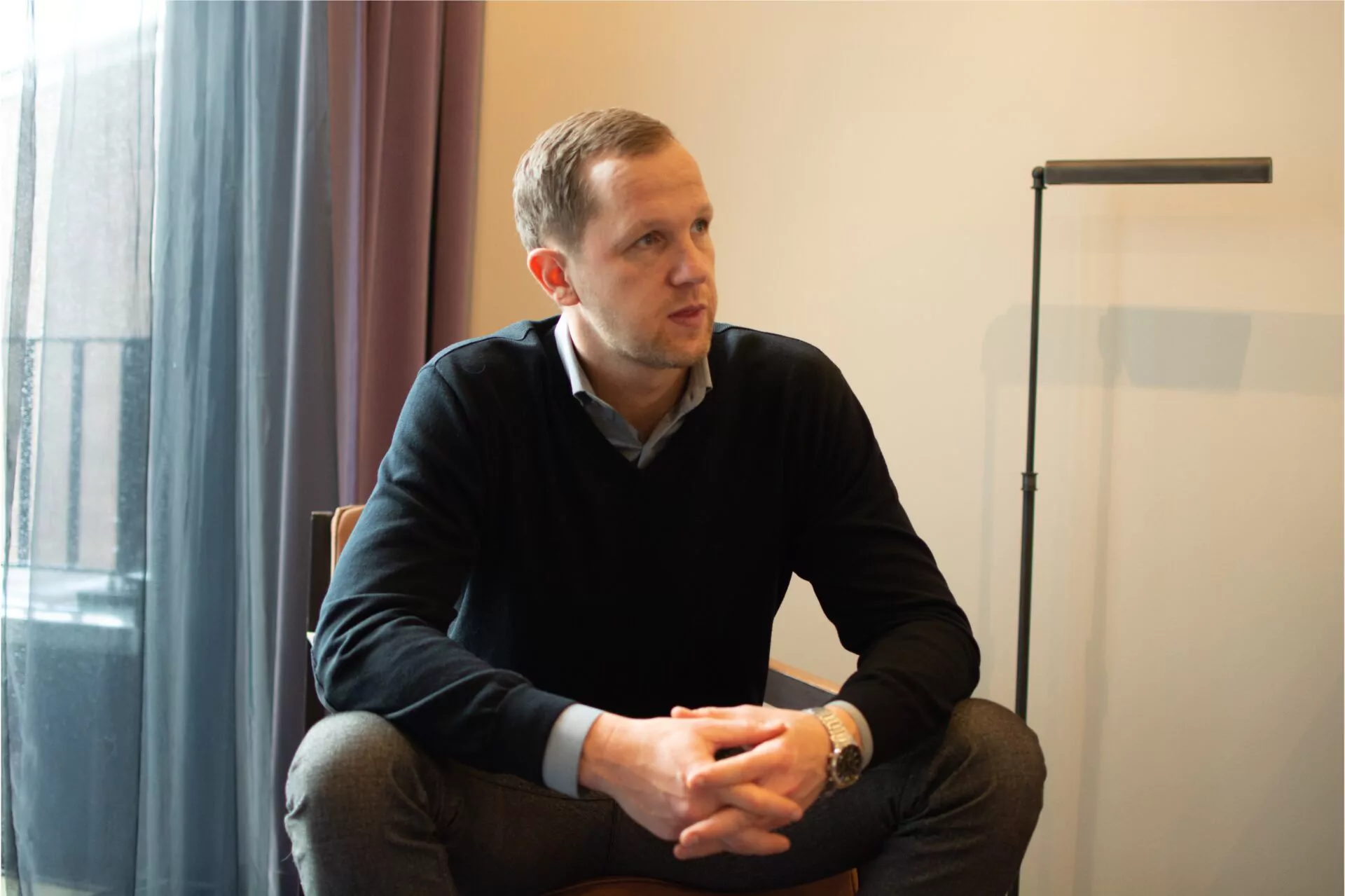 Marcus Jurowski, sitzend vor einer hellen Wand und einem Fenster