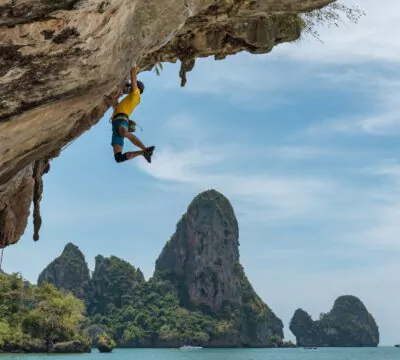 Mann, der kletternd an einem Felsvorsprung hängt