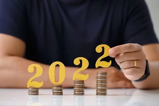 Eine männliche Person, die die Jahreszahl 2022 auf immer höher werdende Münztüren stellt.
