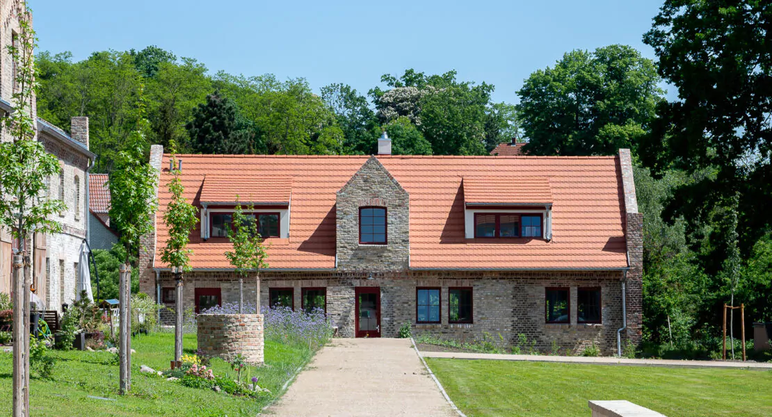 Großes Haus mit Bäumen im Hintergrund angeschlossen an einen großen Garten