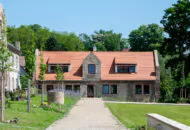 Großes Haus mit Bäumen im Hintergrund angeschlossen an einen großen Garten