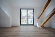 Ein Raum mit Dachschrägen und Holzbalken