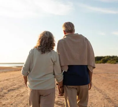 Älteres Paar geht Hand in Hand am Strand entlang bei Sonnenuntergang