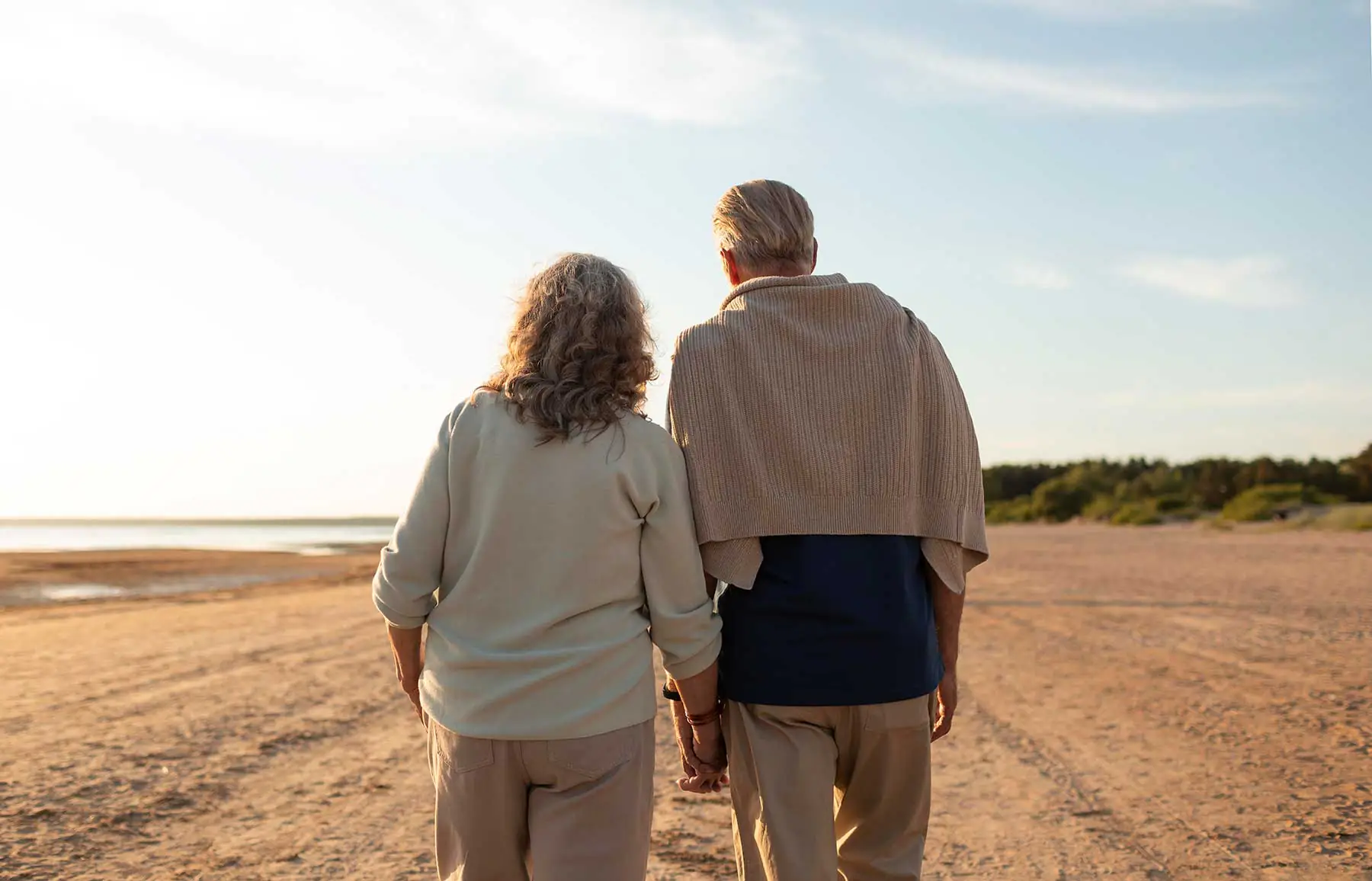 Älteres Paar geht Hand in Hand am Strand entlang bei Sonnenuntergang