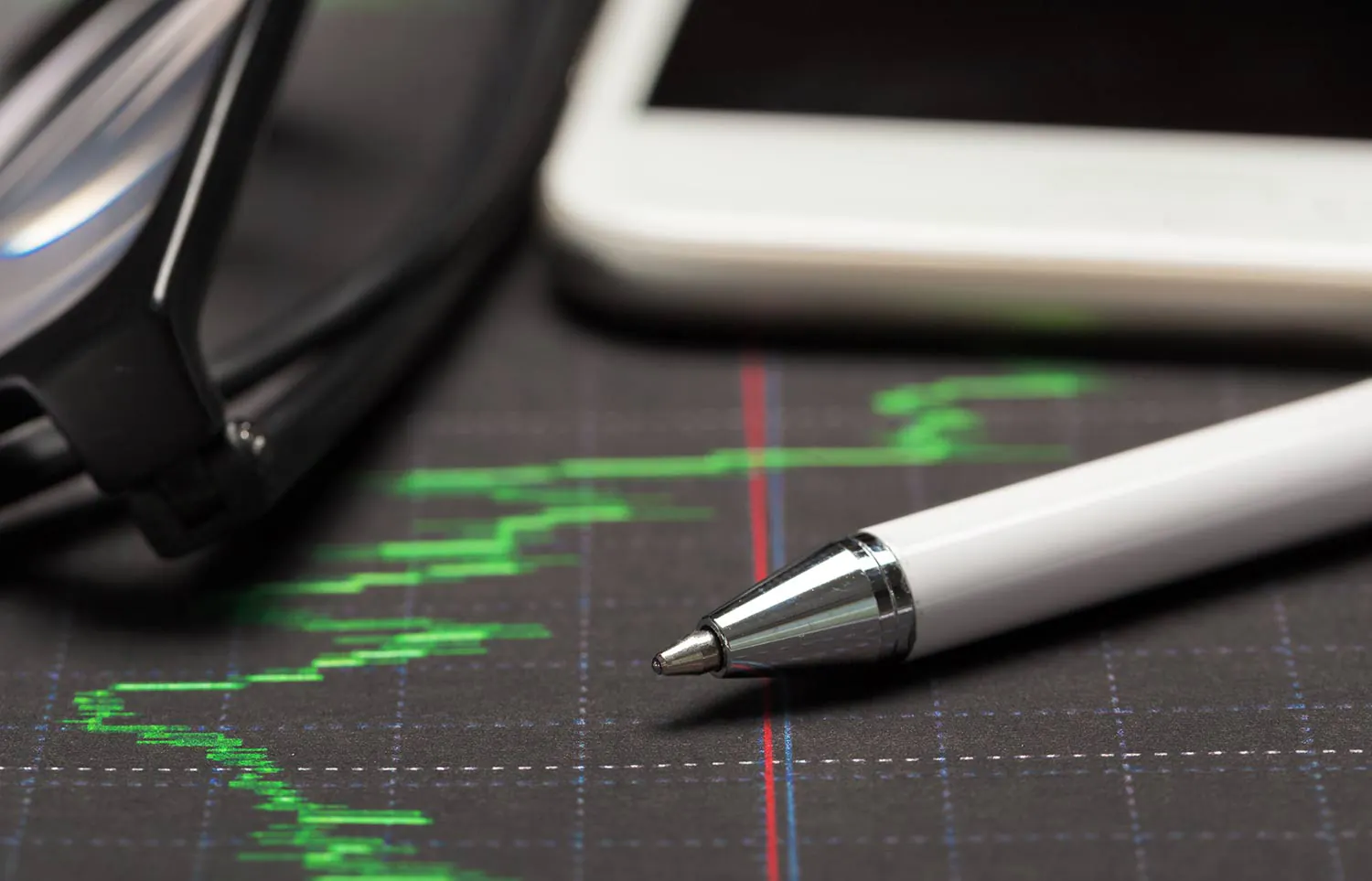 Ein Stift und ein Taschenrechner liegen auf einer Grafik der Wertentwicklung einer Geldanlage