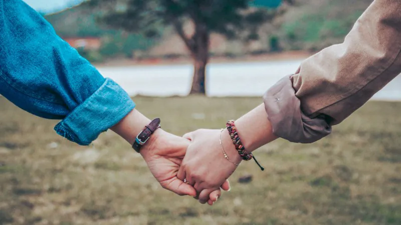 Ein Paar hält die Hände und schaut auf einen Baum